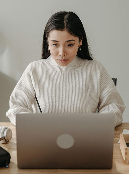 Asian female professional working on a laptop — representing career reinvention and capability growth in the AI era.