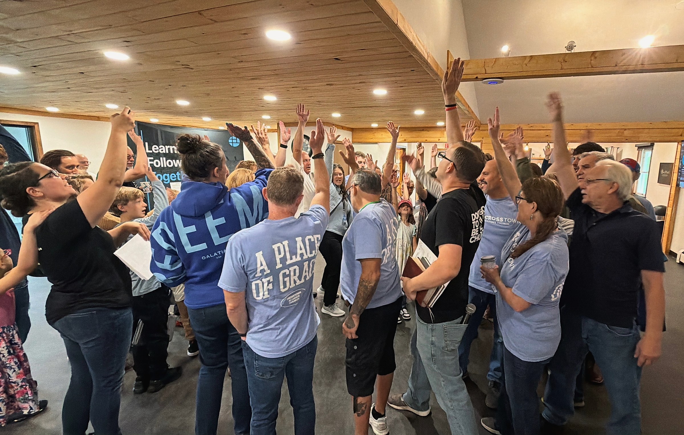 The Crosstown Alliance Church launch team with hands raised as they are sent out to replant a church east of Rochester, New York