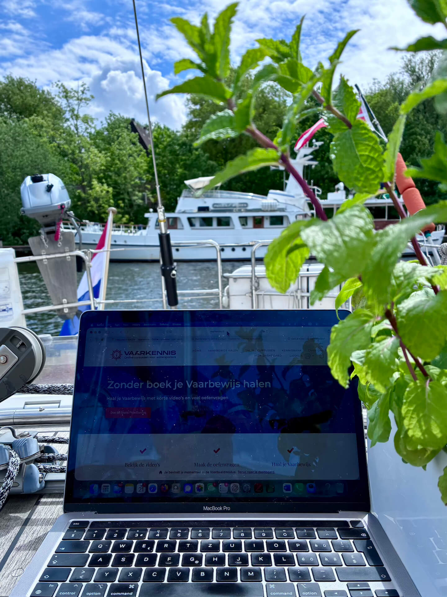 Lieske Sterk werkt aan de Vaarkennis cursussen op haar MacBook aan dek van Lizzy, liggend in de jachthaven van Rendsburg.