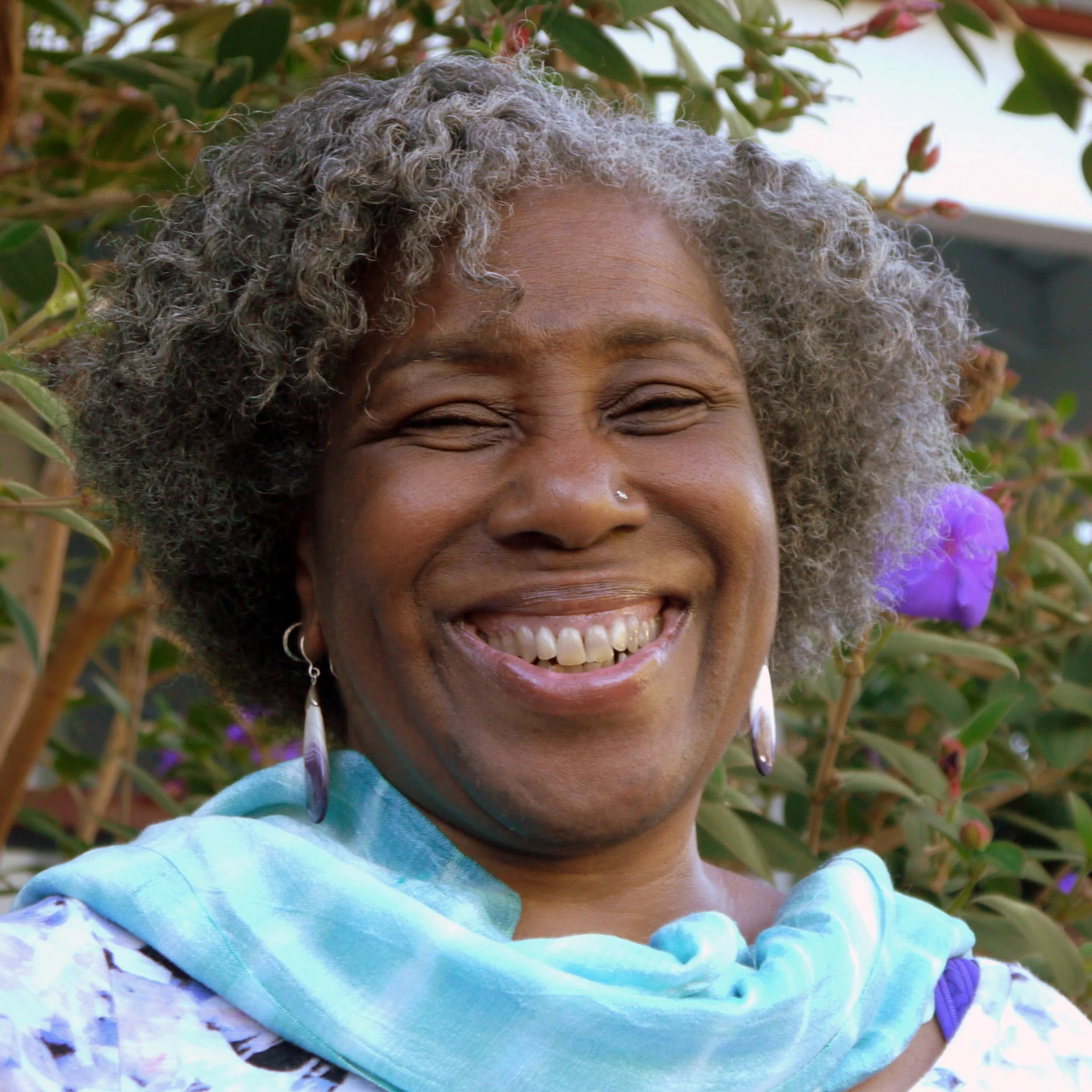 Portrait of teacher DaRa Williams in front of purple flowers.