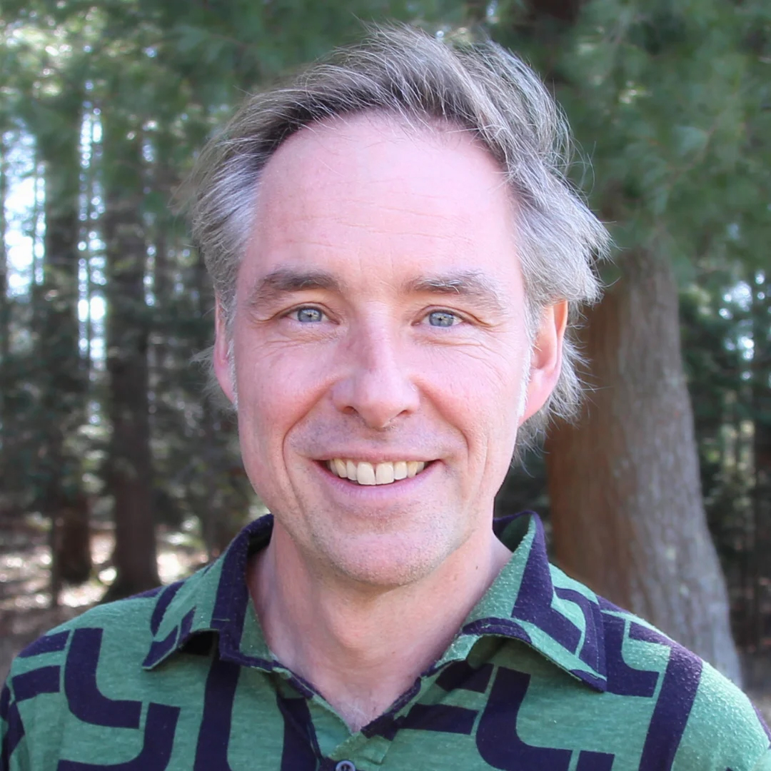 Portrait of teacher Bart van Melik in front of pine trees.