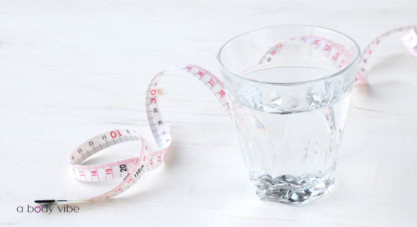Glass of water and measuring tape on a spa table representing body contouring hydration