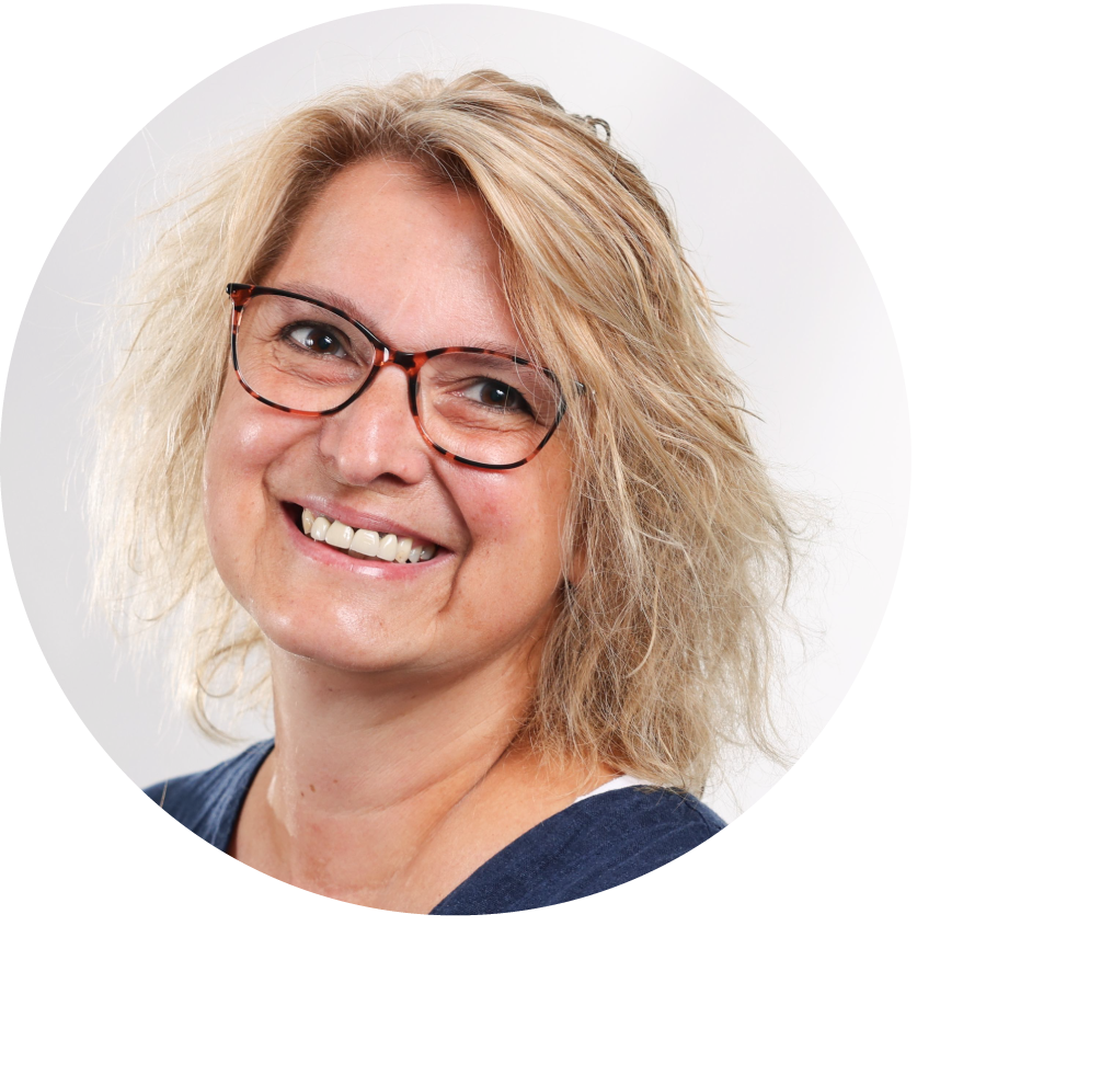 Lachende Kerstin Folgner mit schulterlangen, blonden Haaren und einer braun-orange gemusterten Brille