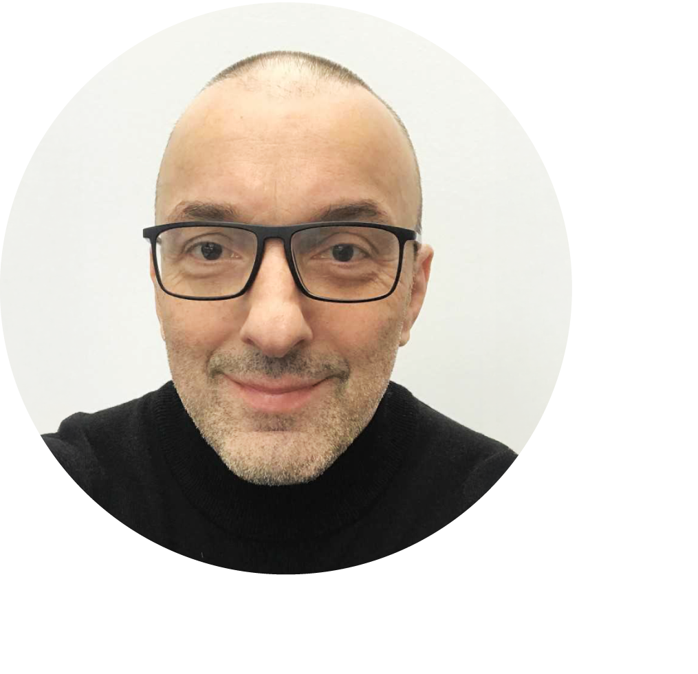 Grinsender Robert D'Amelio mit sehr kurzen dunklen Haaren und einer schwarzen Brille vor einem weißen Hintergrund