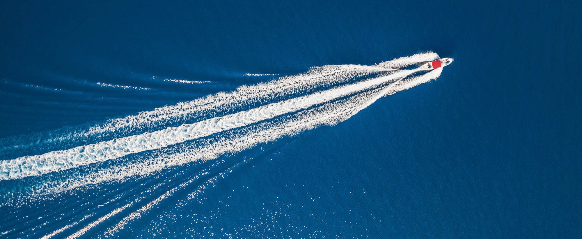 A white trail of water on a blue surfaceDescription automatically generated