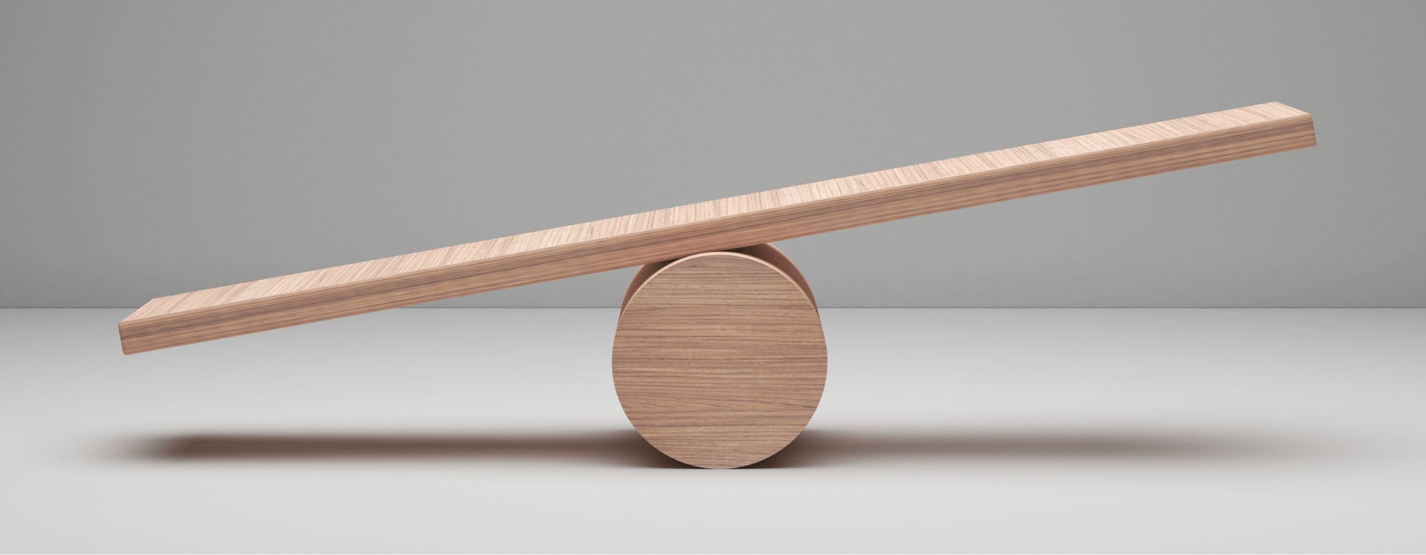 A wooden seesaw on a white surfaceDescription automatically generated
