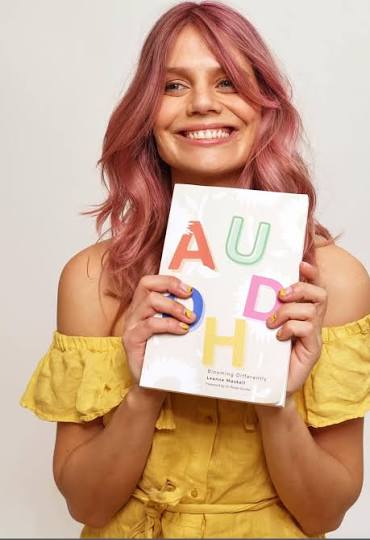 Leanne Maskell holding her book AuDHD: Blooming Differently