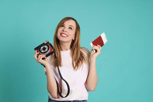 Young pretty woman with camera and passport Young pretty woman with camera and passport on mint background italian passport inside stock pictures, royalty-free photos & images