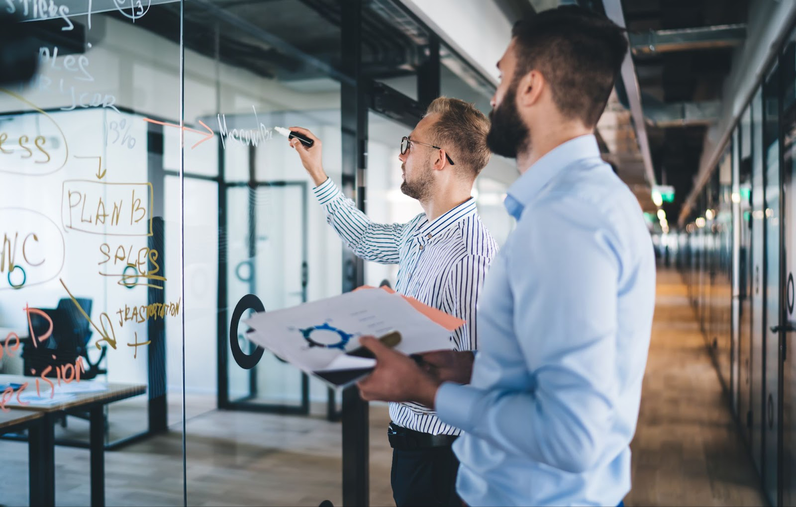Two men planning on a white board