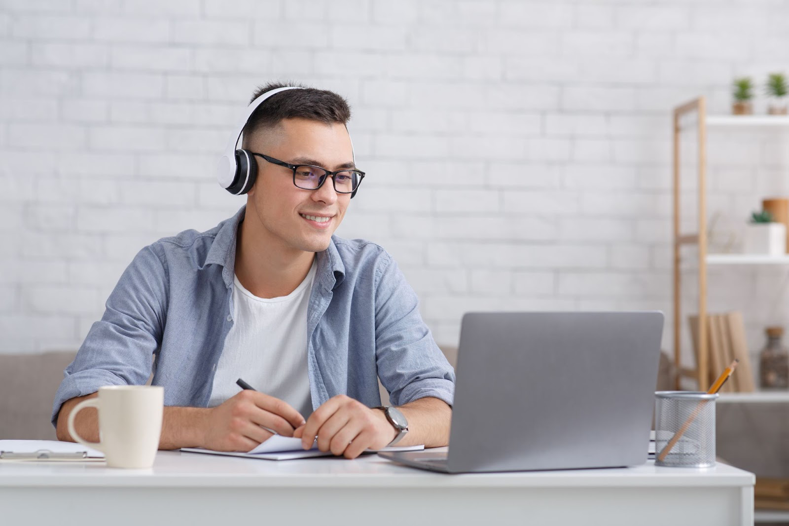 Man wearing headphones and smiling while looking at a laptop computer screen