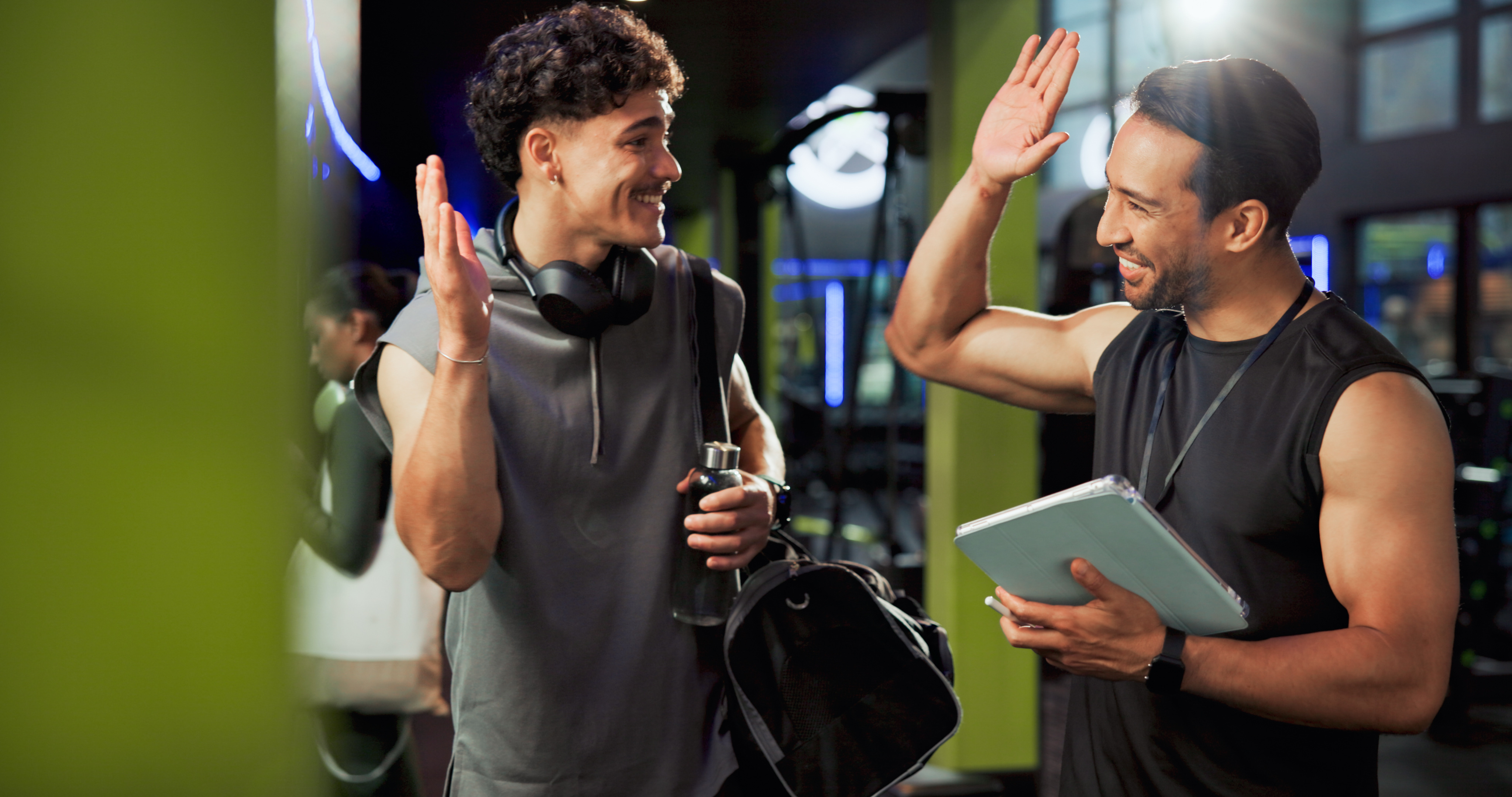 2 guys in gym clothes high five in the centre of a gym
