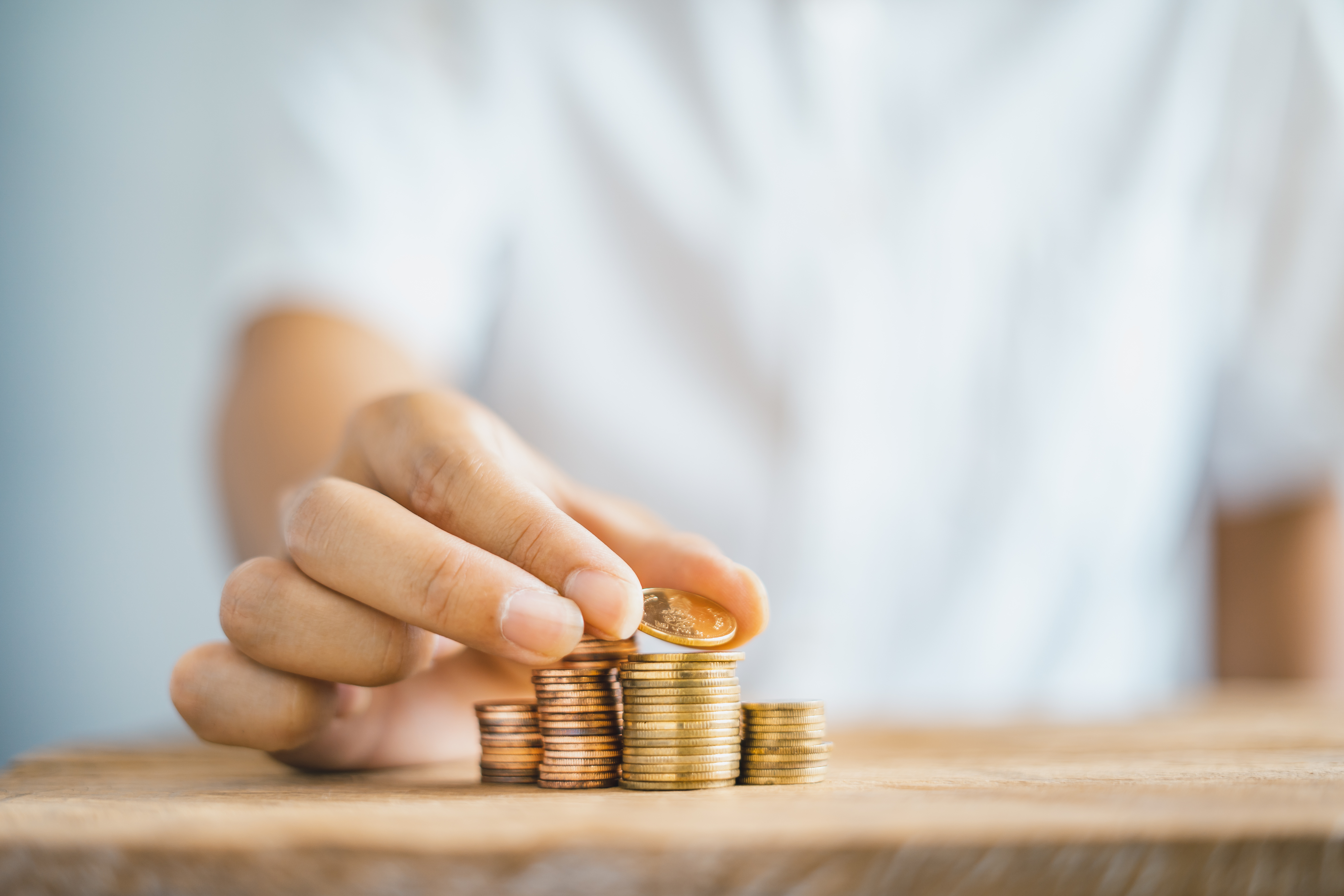 the hand of someone in a white t shirt is counting coins stacked on a table