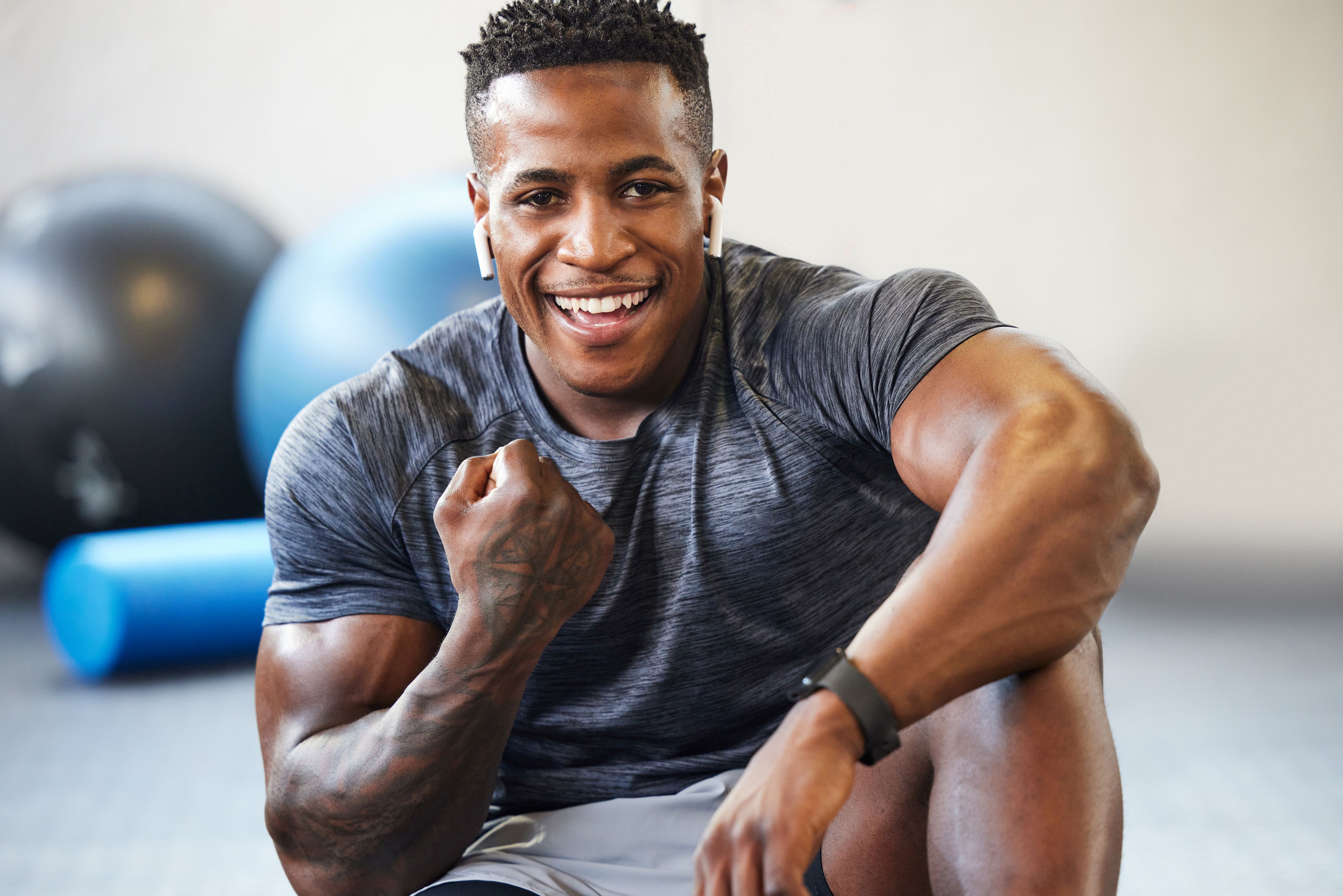 A man seated on teh floor in a gym does a fist pump in celebration