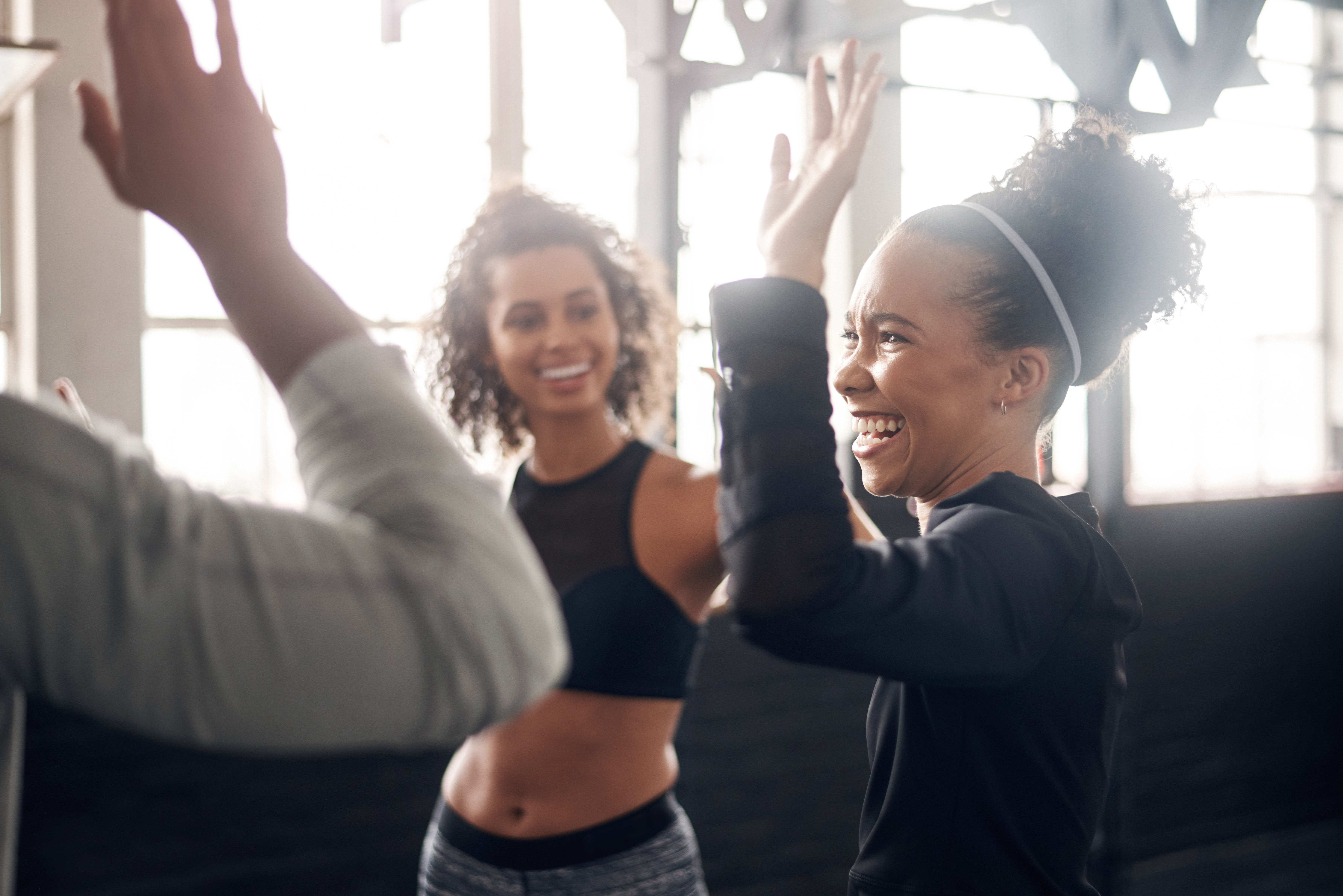 a smiling woman high fives people on either side of her in a gym