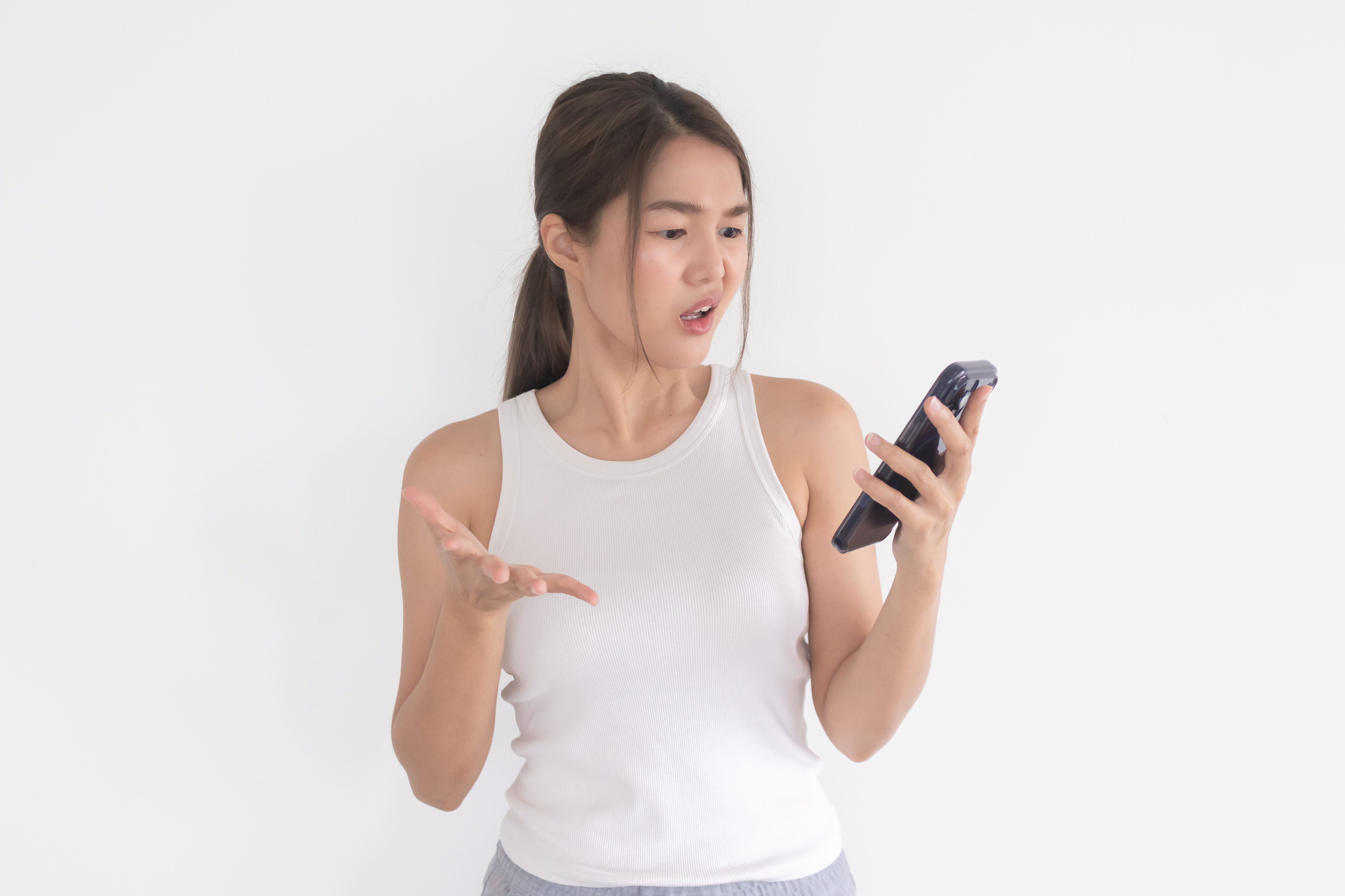 Young Asian Woman Looking at Smartphone with Confused Expression