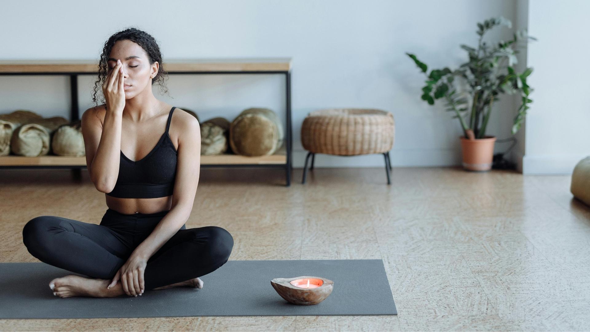 Kimerült nő a jógamatracon ül fáradtan, csukott szemmel