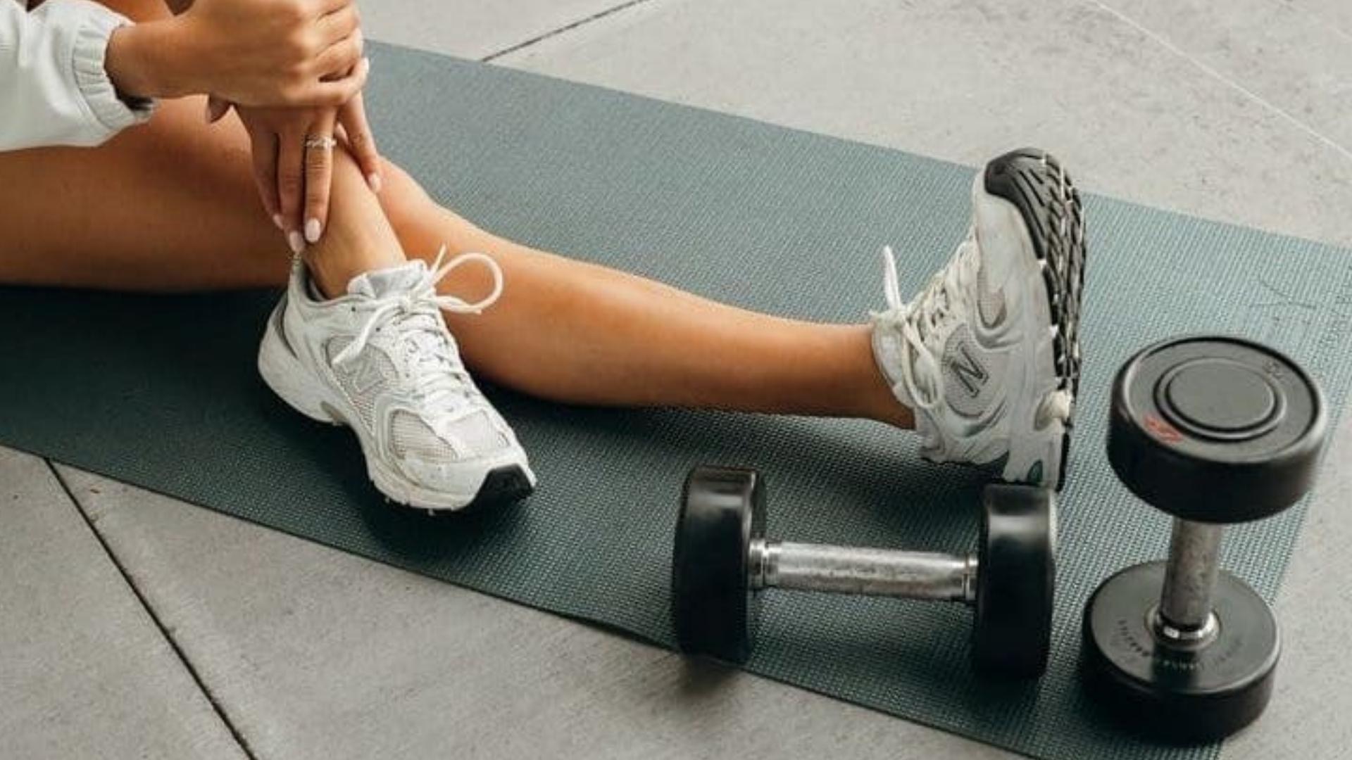 sportos nő ül a jóga matracon, mellette súlyzók