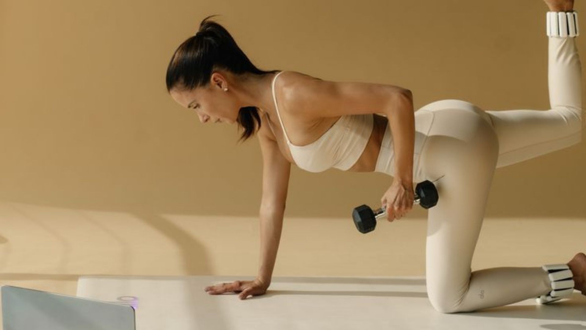 Jógáző fitt nő a matracon kézisúlyzóval tornázik