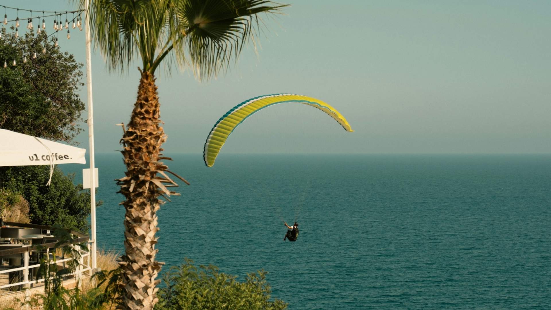 ejtőernyős ember a tenger felett, pálmafás parton a vakáción