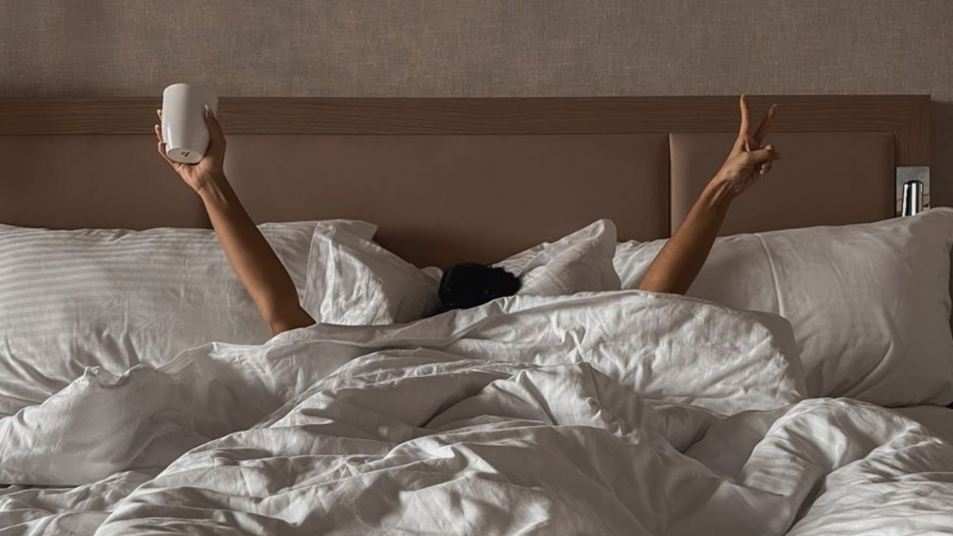 Ágyban kávézó nő nyújtózkodik