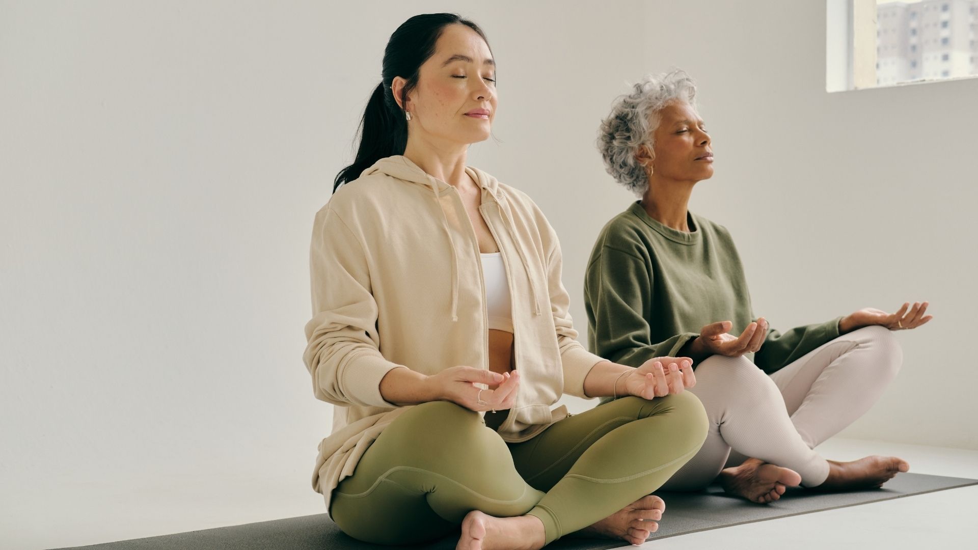 Idősebb és fiatalabb kiegyensúlyozott nők jógáznak