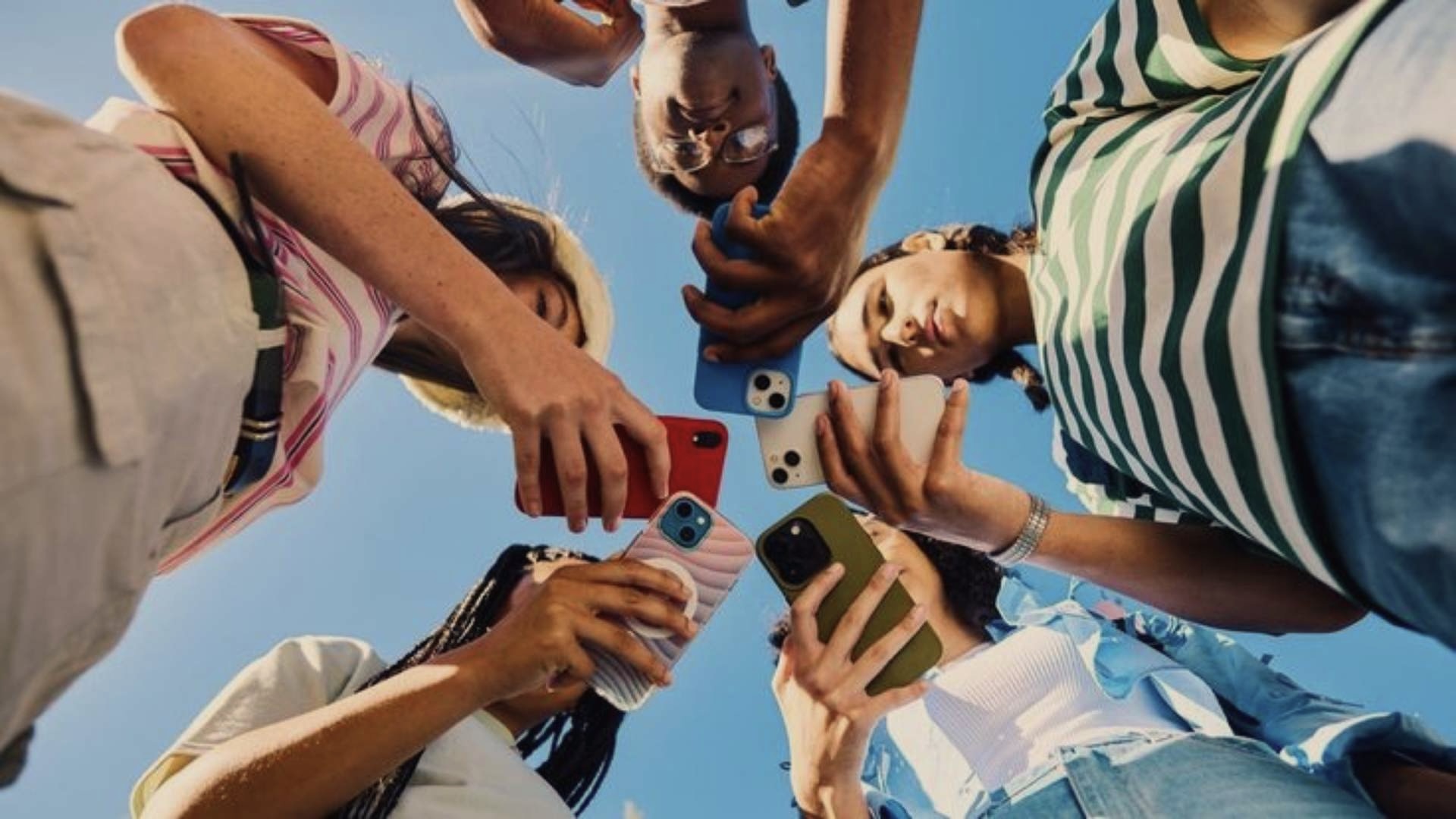 fiatalok állnak körben és nézik a telefonjukat